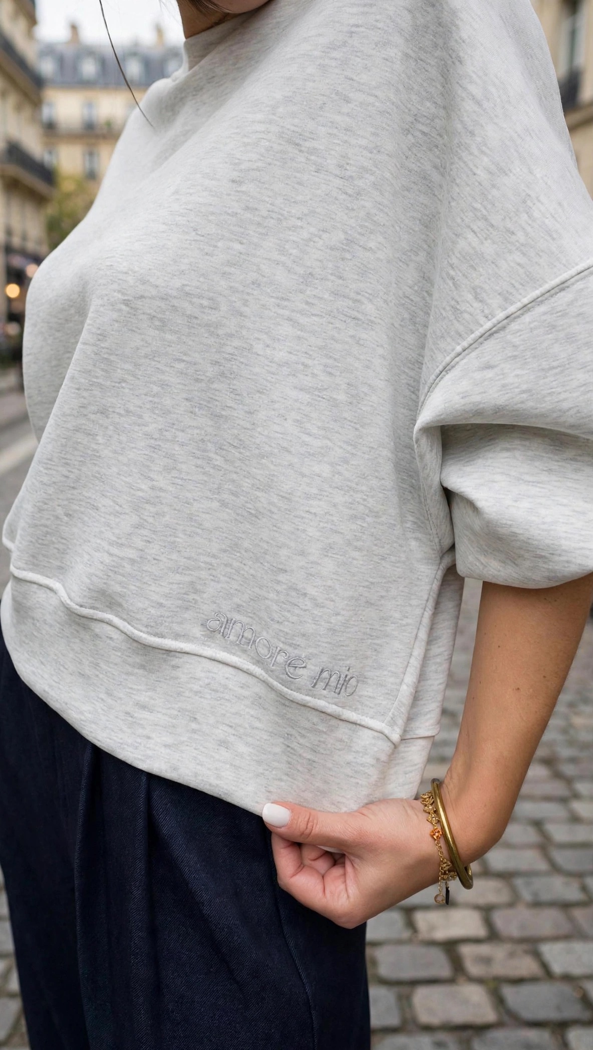 Femme portant un sweatshirt gris clair oversize et un pantalon large bleu marine taille haute, une tenue chic et décontractée pour femme.